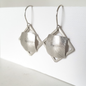 Statement silver dangle earrings hanging on the stand