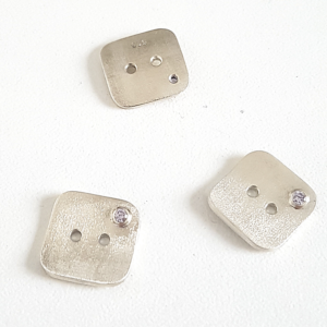 Artisan Custom Minimalist Silver CZ Apparel 3 Buttons are placed on the white surface.