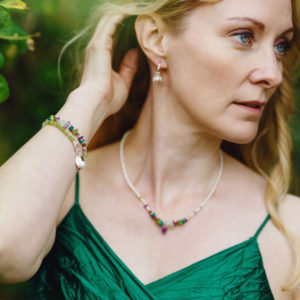 Woman in garden wearing Gemstone jewellery, green peridot purple amethyst, white pearl