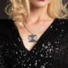 Blond woman wearing a sparkling black dress and an elegant silver square pendant on a black background