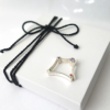 Contemporary silver gemstone ring is placed on the white gift box tied with black cotton string.