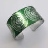 green cuff with silvery coloured scroll motif seen from above
