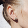 Circle silver stud earrings on an earlobe.